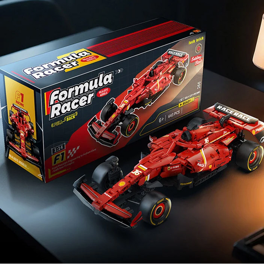 A red Formula Racer toy building block model of an F1 race car shown next to its retail box on a dark tabletop. The packaging features bold red, black, and yellow branding, and the model itself has black tires with yellow and white accents.